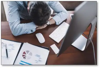 A man sitting at his desk with his head down.